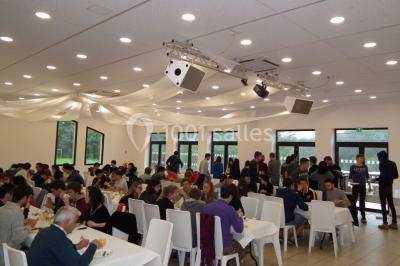 Un groupe de personnes assises en cercle en plein air, discutant près d'un tableau blanc, entouré d'arbres.