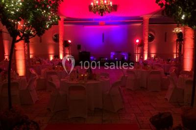 Façade d'un château entouré de jardins bien entretenus, avec un ciel nuageux en arrière-plan.