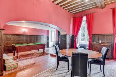 Façade d'un château entouré de jardins bien entretenus, avec un ciel nuageux en arrière-plan.