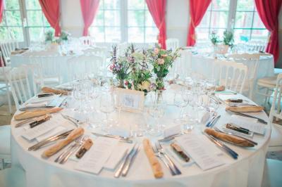 Façade d'un château entouré de jardins bien entretenus, avec un ciel nuageux en arrière-plan.