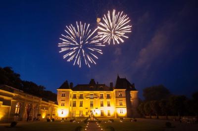 Façade d'un château entouré de jardins bien entretenus, avec un ciel nuageux en arrière-plan.