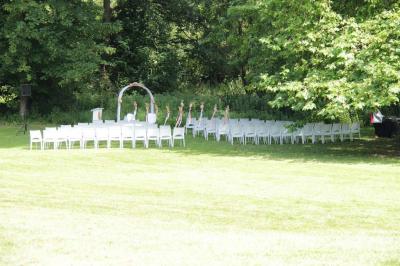 Façade d'un château entouré de jardins bien entretenus, avec un ciel nuageux en arrière-plan.