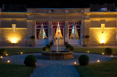 Façade d'un château entouré de jardins bien entretenus, avec un ciel nuageux en arrière-plan.