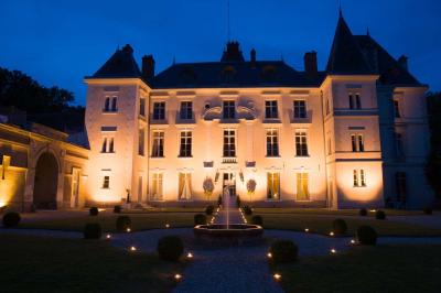 Façade d'un château entouré de jardins bien entretenus, avec un ciel nuageux en arrière-plan.