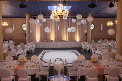 Façade d'un château entouré de jardins bien entretenus, avec un ciel nuageux en arrière-plan.