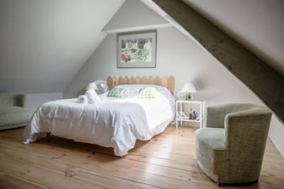 Dortoir lumineux avec plusieurs lits simples alignés, draps blancs et cartes géographiques accrochées aux murs.