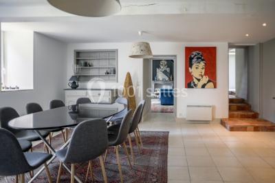 Dortoir lumineux avec plusieurs lits simples alignés, draps blancs et cartes géographiques accrochées aux murs.