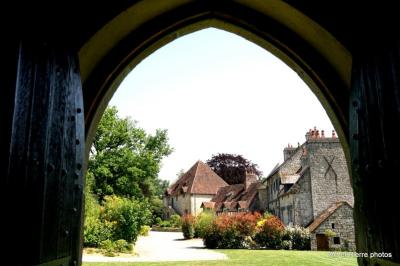 Dortoir lumineux avec plusieurs lits simples alignés, draps blancs et cartes géographiques accrochées aux murs.