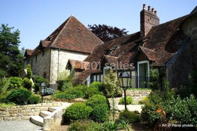 Dortoir lumineux avec plusieurs lits simples alignés, draps blancs et cartes géographiques accrochées aux murs.