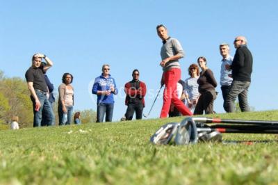 Vue nocturne d'une maison en bois éclairée, entourée d'arbres illuminés, sous un ciel nuageux avec la lune visible.