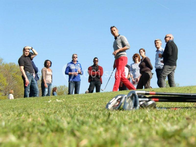 Un groupe de personnes debout sur une pelouse par une journée ensoleillée, avec des clubs de golf au premier plan.