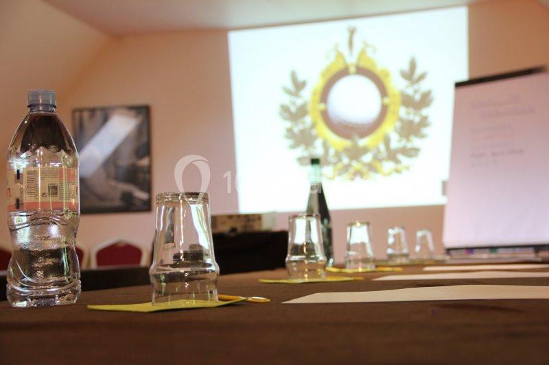 Salle de réunion avec une table dressée, des verres, une bouteille d'eau et un écran de projection en arrière-plan.