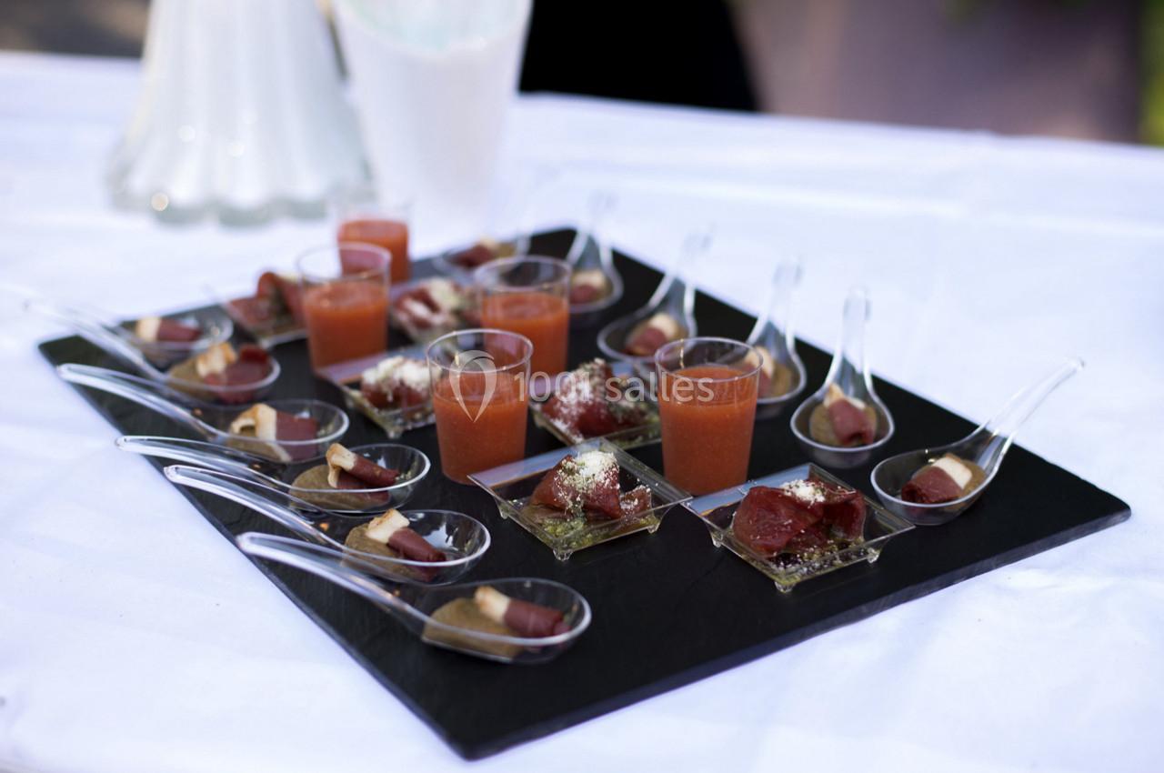 Plateau de verrines et cuillères apéritives contenant des préparations colorées, disposé sur une table blanche.