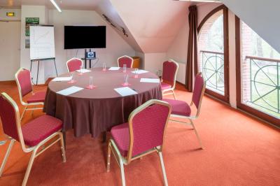 Vue nocturne d'une maison en bois éclairée, entourée d'arbres illuminés, sous un ciel nuageux avec la lune visible.