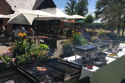 Vue nocturne d'une maison en bois éclairée, entourée d'arbres illuminés, sous un ciel nuageux avec la lune visible.