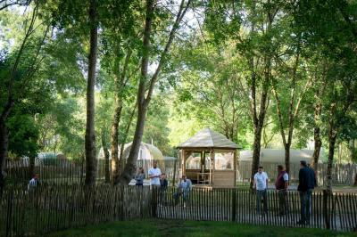 Espace extérieur décoré avec arche florale, deux chaises transparentes et fond blanc sous une tente.
