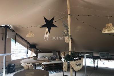 Espace extérieur décoré avec arche florale, deux chaises transparentes et fond blanc sous une tente.