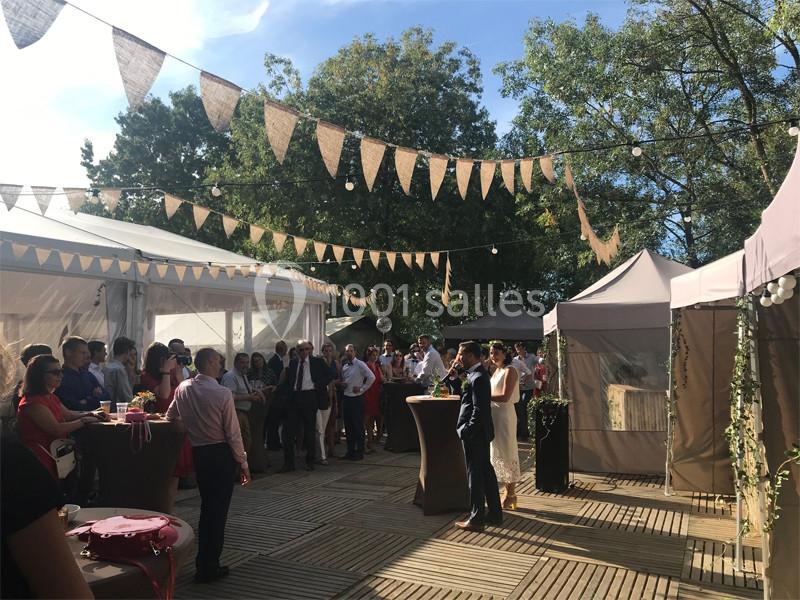 Un groupe de personnes rassemblées dans un espace extérieur décoré de guirlandes et de tentes lors d'un événement.