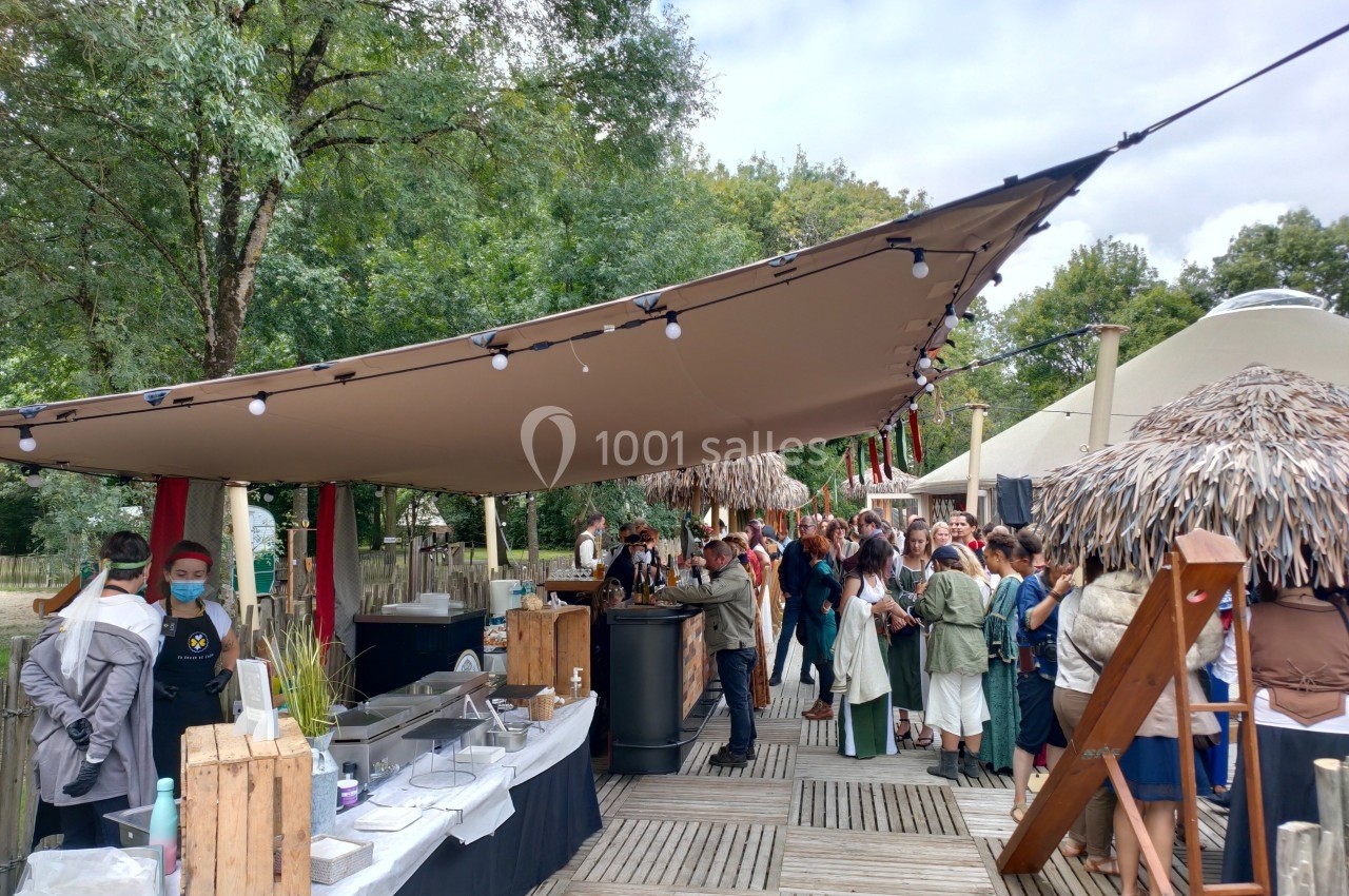 Des personnes font la queue devant un stand de restauration en plein air, sous une grande toile tendue.
