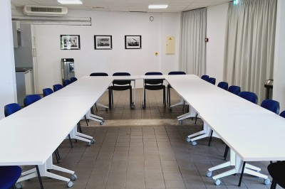 Terrasse d'un restaurant en bois avec vue sur un port de plaisance, tables occupées et végétation en premier plan.