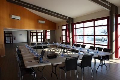 Terrasse d'un restaurant en bois avec vue sur un port de plaisance, tables occupées et végétation en premier plan.