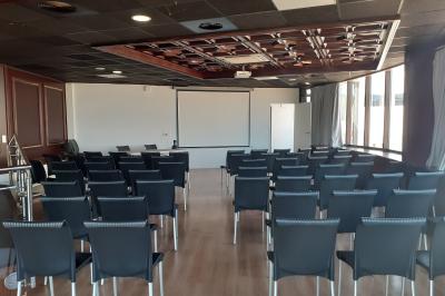 Terrasse d'un restaurant en bois avec vue sur un port de plaisance, tables occupées et végétation en premier plan.