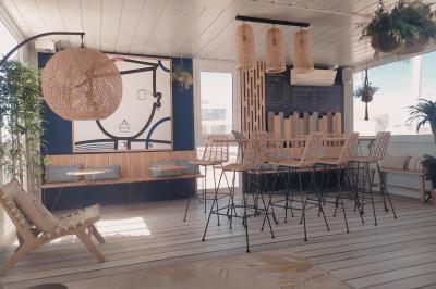 Terrasse d'un restaurant en bois avec vue sur un port de plaisance, tables occupées et végétation en premier plan.