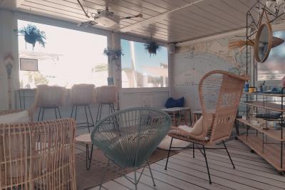 Terrasse d'un restaurant en bois avec vue sur un port de plaisance, tables occupées et végétation en premier plan.