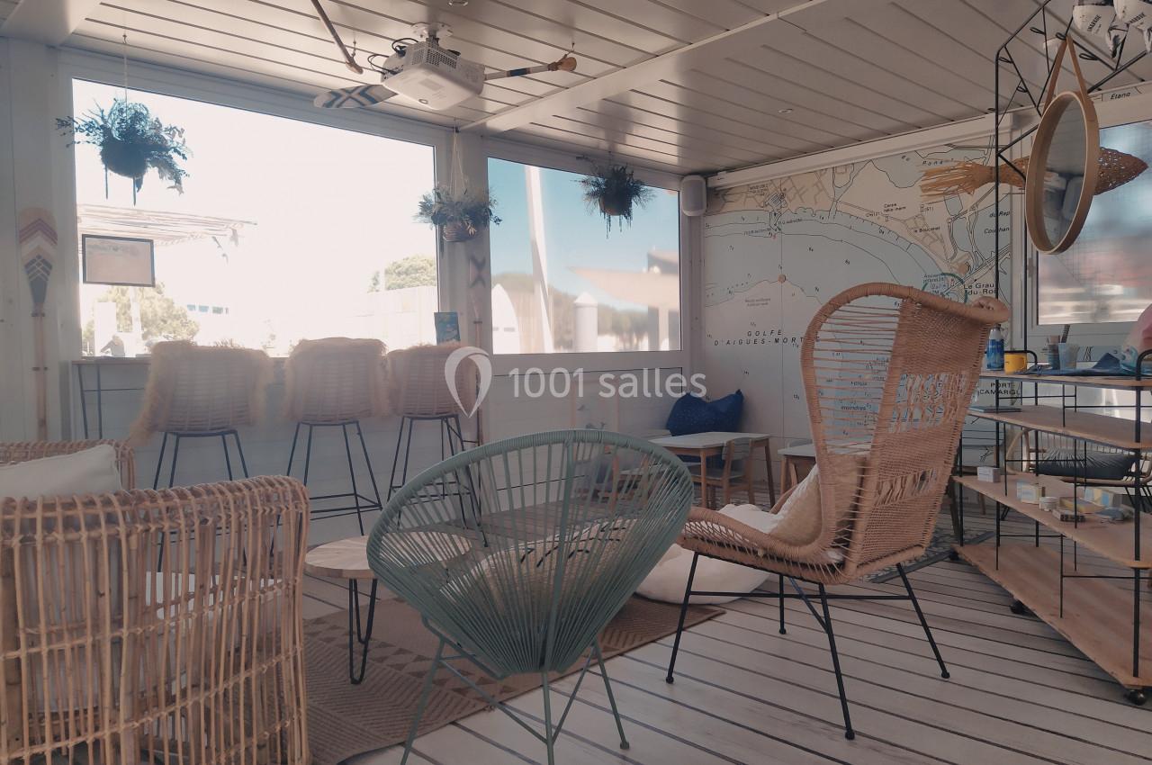 Espace intérieur lumineux avec mobilier en rotin et métal, décoré de plantes suspendues et d'une carte murale.