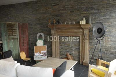 Salon avec cheminée en bois, mur en pierre, mobilier éclectique et éléments décoratifs comme bougies et lampadaire.