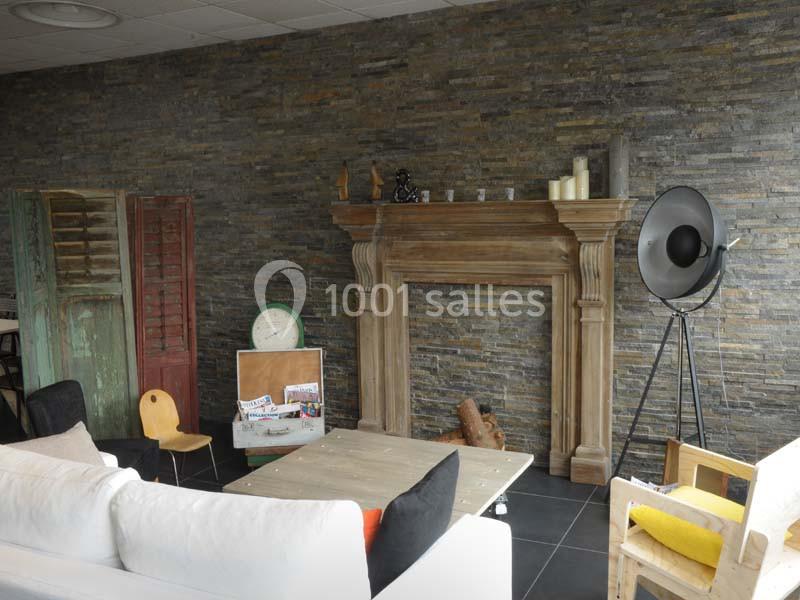 Salon avec cheminée en bois, mur en pierre, mobilier éclectique et éléments décoratifs comme bougies et lampadaire.