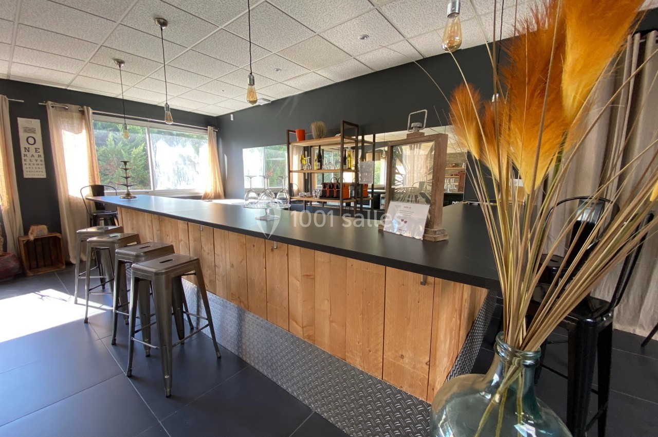 Comptoir en bois avec tabourets hauts dans une pièce lumineuse, décorée de plantes séchées et d'étagères modernes.