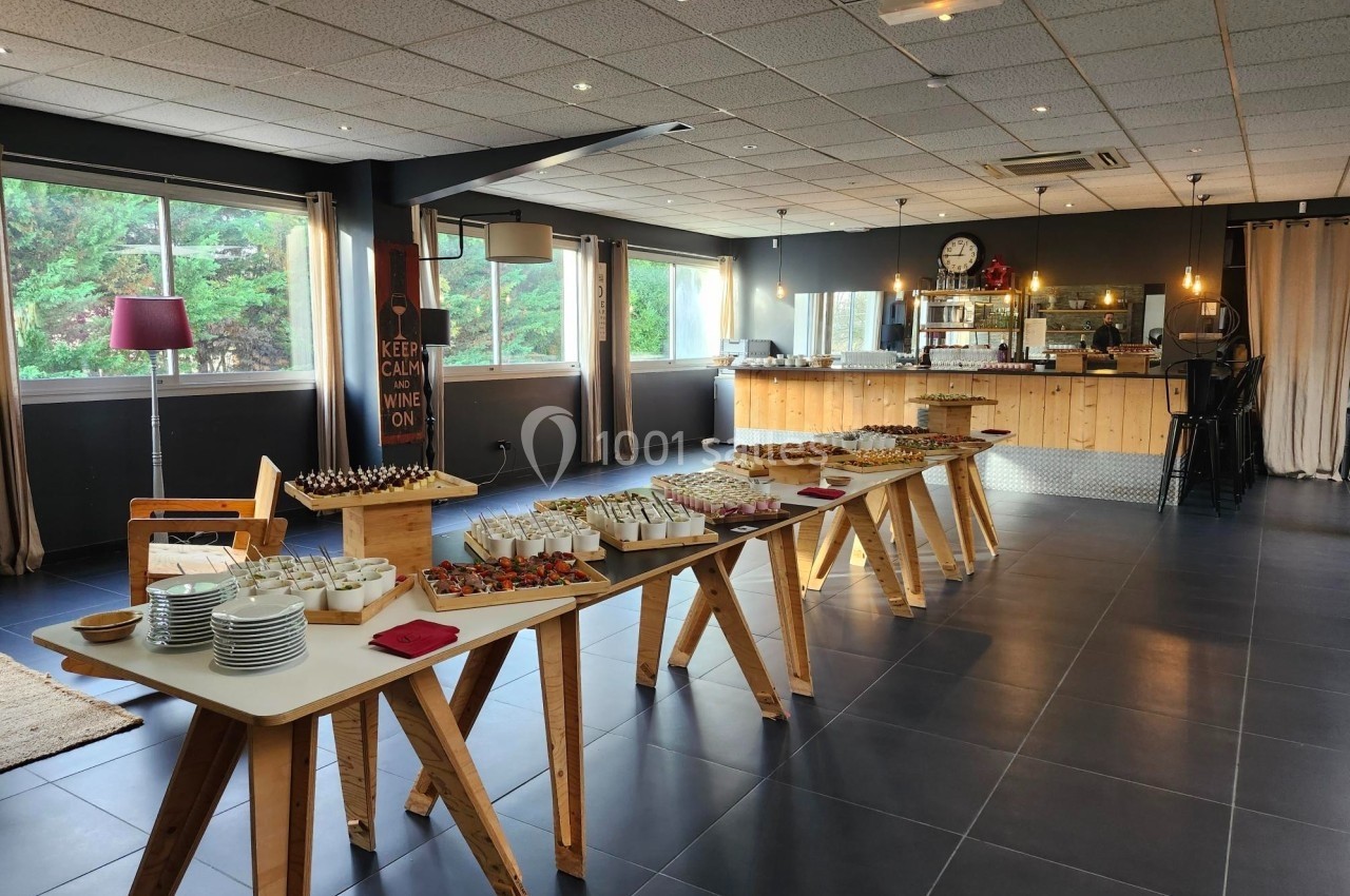 Salle lumineuse avec buffet dressé sur des tables en bois, offrant divers plats et desserts dans un cadre moderne.