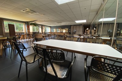 Miniature Location salle Trappes (Yvelines) - Mets En Scène #1 Salle lumineuse avec tables blanches, chaises en métal ajouré, grandes fenêtres et miroirs sur un mur.