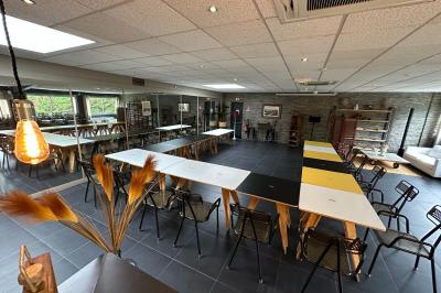 Salle moderne avec tables colorées en bois, chaises métalliques, grand miroir et comptoir en arrière-plan.