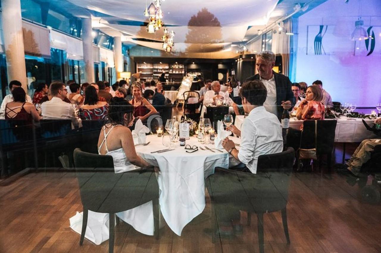 Des convives dînent dans un restaurant élégant, éclairé par des lumières tamisées et des lustres.