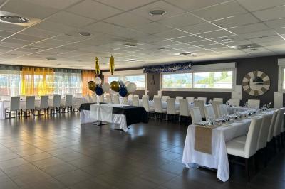 Terrasse extérieure couverte avec tables et chaises en osier, éclairée par des lumières suspendues, de nuit.