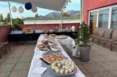 Terrasse extérieure couverte avec tables et chaises en osier, éclairée par des lumières suspendues, de nuit.