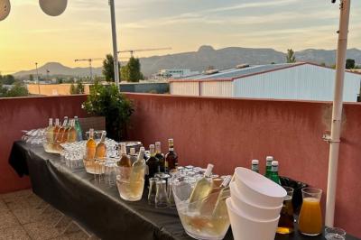 Terrasse extérieure couverte avec tables et chaises en osier, éclairée par des lumières suspendues, de nuit.