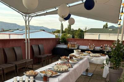Terrasse extérieure couverte avec tables et chaises en osier, éclairée par des lumières suspendues, de nuit.