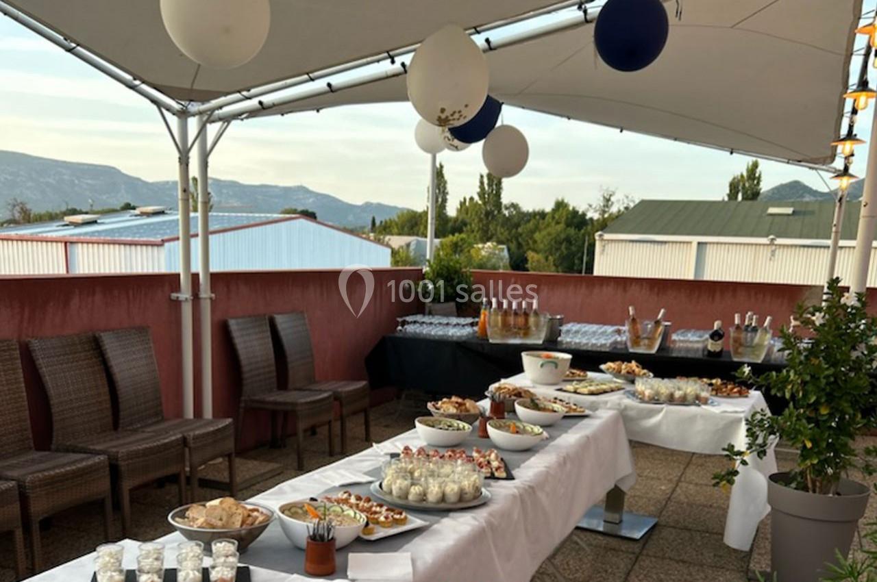 Buffet en extérieur sous une tente avec des plats variés, des boissons et une vue sur des montagnes en arrière-plan.