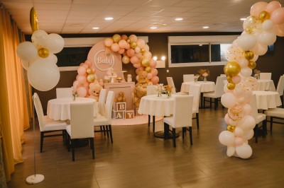 Terrasse extérieure couverte avec tables et chaises en osier, éclairée par des lumières suspendues, de nuit.