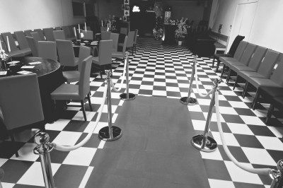 Terrasse extérieure couverte avec tables et chaises en osier, éclairée par des lumières suspendues, de nuit.