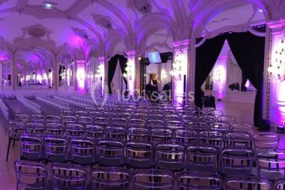 Salon avec fauteuils colorés, piano rose, bar en arrière-plan et décorations modernes dans une ambiance chaleureuse.