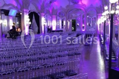 Salon avec fauteuils colorés, piano rose, bar en arrière-plan et décorations modernes dans une ambiance chaleureuse.