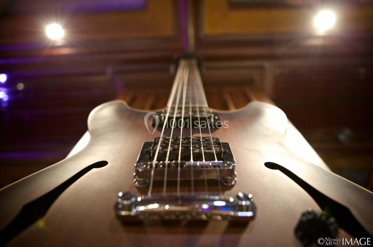 Vue rapprochée d'une guitare électrique semi-hollow prise en contre-plongée, mettant en valeur les cordes et les micros.