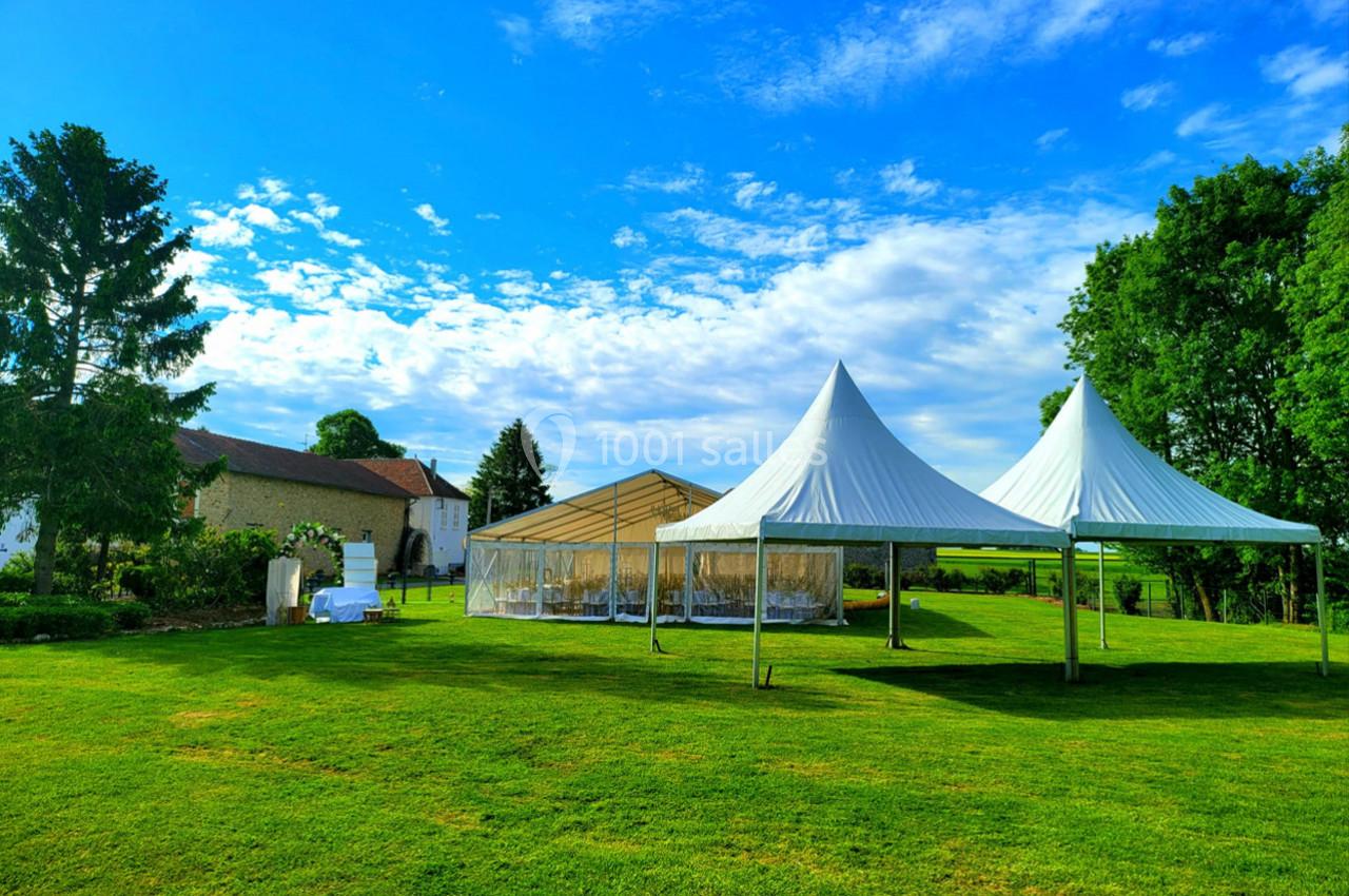 Deux grandes tentes blanches et une structure transparente installées sur une pelouse verdoyante par temps ensoleillé.