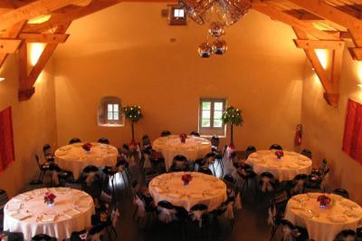 Miniature Location salle Montregard (Haute-Loire) - Château de Marcoux #5 Cour extérieure avec table et chaises en métal, entourée de murs en pierre, d'un bâtiment en pierre et d'arbres.