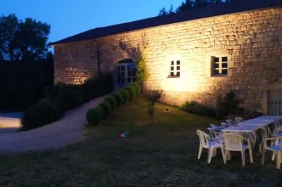 Miniature Location salle Montregard (Haute-Loire) - Château de Marcoux #3 Cour extérieure avec table et chaises en métal, entourée de murs en pierre, d'un bâtiment en pierre et d'arbres.