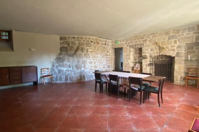 Miniature Location salle Montregard (Haute-Loire) - Château de Marcoux #11 Cour extérieure avec table et chaises en métal, entourée de murs en pierre, d'un bâtiment en pierre et d'arbres.